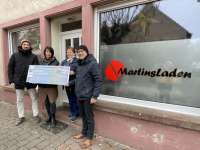 Spendenübergabe vor dem Eingang des Martinladens